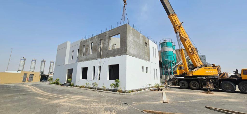 Two-storey precast concrete building under construction with a mobile crane