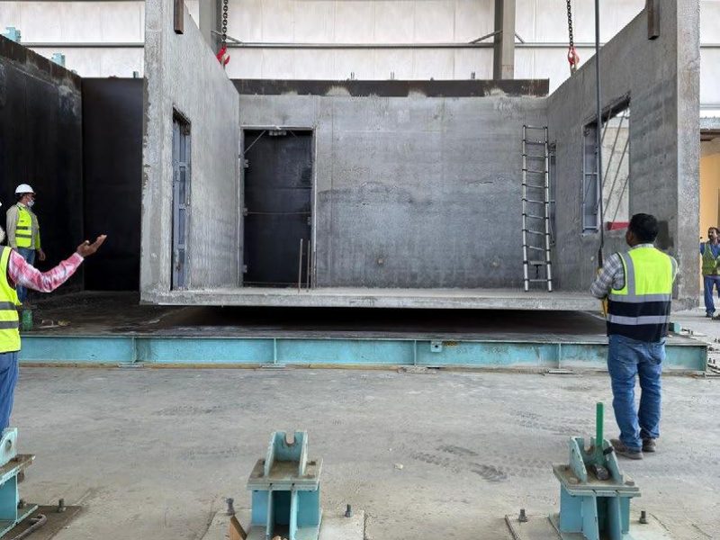 Site crew erecting precast concrete wall panels on a foundation slab